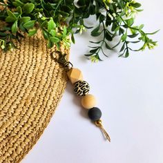 a close up of a keychain on a table next to a plant with leaves