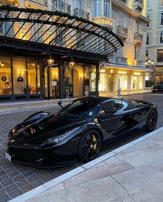 a black sports car parked in front of a hotel