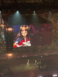 a large screen in the middle of an arena with people on it and one person holding a microphone