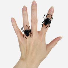 a hand with two fake black spider rings on it's fingers and one is holding the other