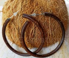 two wooden hoop earrings sitting on top of a pile of hay