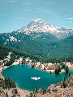 a lake surrounded by mountains and trees with snow on the mountain top in the distance