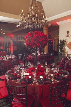 a dining room set up for a formal function with red flowers on the tables and centerpieces