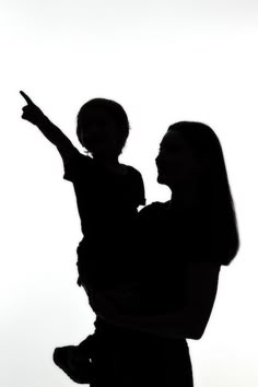 a woman holding a child in her arms and pointing at something on the other side