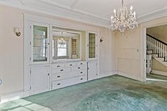 an empty room with a chandelier and white cabinets