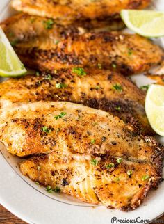 grilled chicken with limes and parsley on a white plate