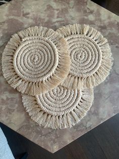 three woven coasters sitting on top of a marble table with brown and white paint