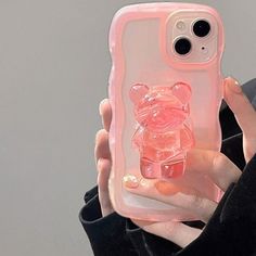 a person holding up a pink phone case with a bear on it