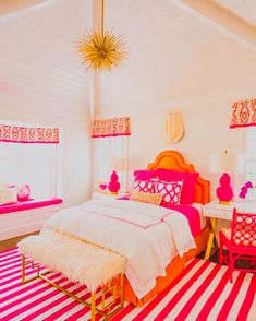 a bedroom decorated in pink and white with striped rugs