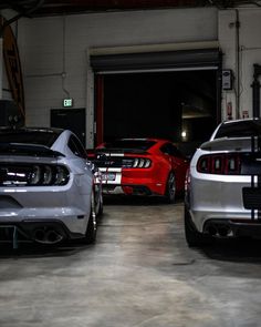 two cars parked in a garage next to each other with their hoods down and the lights on