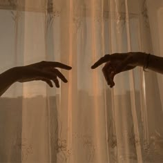 two hands reaching towards each other in front of curtains