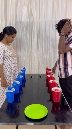 two women are standing at a table with cups on it and one woman is holding a frisbee