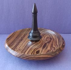 a small wooden stand with a black metal tip on it's end and a purple background