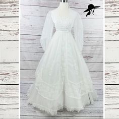 a white wedding dress with long sleeves and lace on the skirt is displayed in front of a