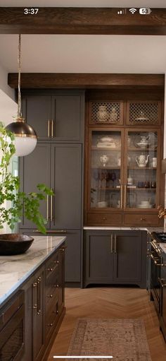 a kitchen with wooden floors and gray cabinets, white counter tops and an area rug on the floor