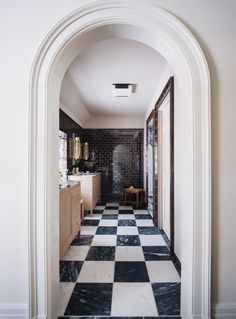 an arched hallway leading to a bathroom with black and white checkered tile flooring