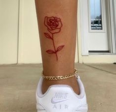 a rose tattoo on the ankle is shown in red ink with a gold chain around it