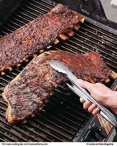 someone is grilling ribs on the grill with tongs and a spatula in their hand