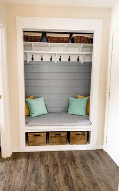 a bench with two pillows and some baskets on top of it next to a door