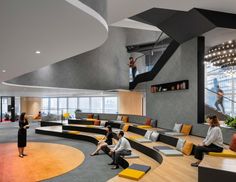 people are sitting and standing in an office lobby with large circular seating areas on the floor