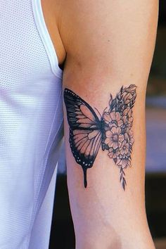 a woman's arm with a butterfly and flowers tattoo on the left side of her arm