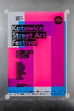 a poster for the festival is displayed on a metal surface with pink, blue and purple squares