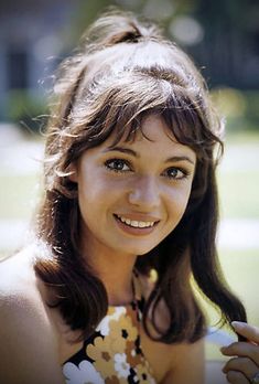 a woman in a flowered dress is smiling for the camera