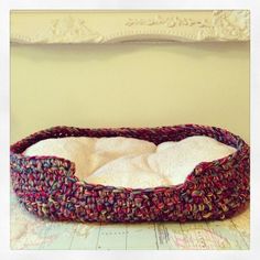 a dog bed made out of knitted material on top of a table with a map in the background