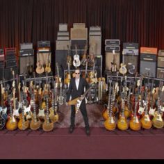 a man standing in front of guitars and amps