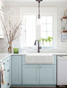 a kitchen with blue cabinets and white walls, an oven, dishwasher and sink