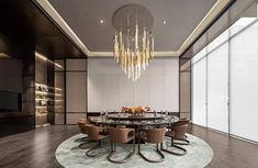 a dining room with a round table surrounded by brown chairs and chandelier hanging from the ceiling