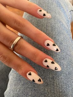 a woman's hand with white and black hearts painted on it, while sitting down