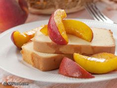 a white plate topped with slices of bread and sliced peaches next to a bowl of fruit