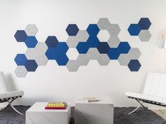 a living room with two white chairs and a wall made out of hexagonal tiles