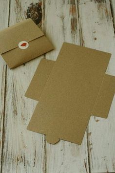 two brown envelopes sitting next to each other on top of a white wooden table