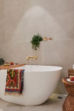 a bathroom with a large white bathtub next to a plant on the wall and rug