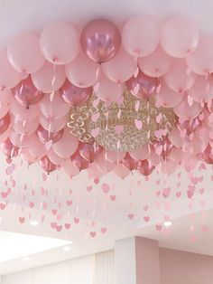 pink and gold balloons are hanging from the ceiling in a room with hearts on it