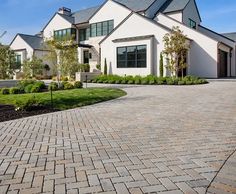 a large white house sitting on top of a lush green field next to a driveway