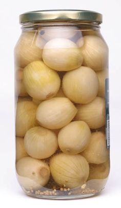 a glass jar filled with onions on top of a table