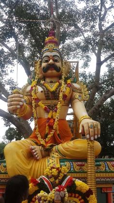 a statue of a man sitting on top of a tree