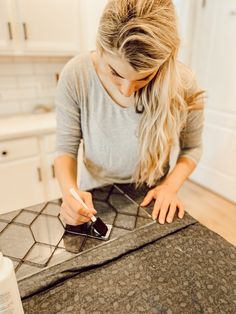 a woman sitting at a table with a cell phone in her hand and writing on it