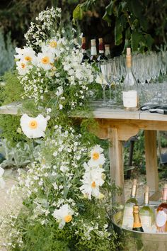 an outdoor bar set up with flowers and wine glasses on the table next to it