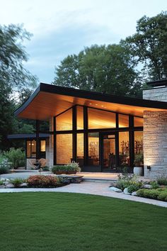 a modern house in the middle of a lush green park at night with lights on