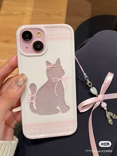 a person holding up a phone case with a cat on it and a pink ribbon