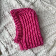 a pink knitted mitt laying on top of a bed