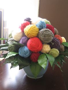 a vase filled with balls of yarn on top of a wooden table