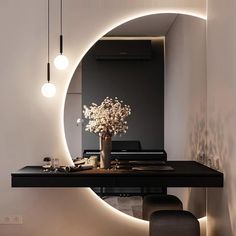 a black table with a vase and flowers on it in front of a round mirror