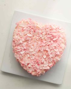 a heart shaped cake sitting on top of a white cutting board next to a knife