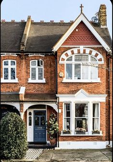 a large brick house with white trim and arched windows on the front, along side a blue door