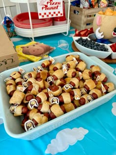 a table topped with lots of hot dogs covered in marshmallows and other toppings